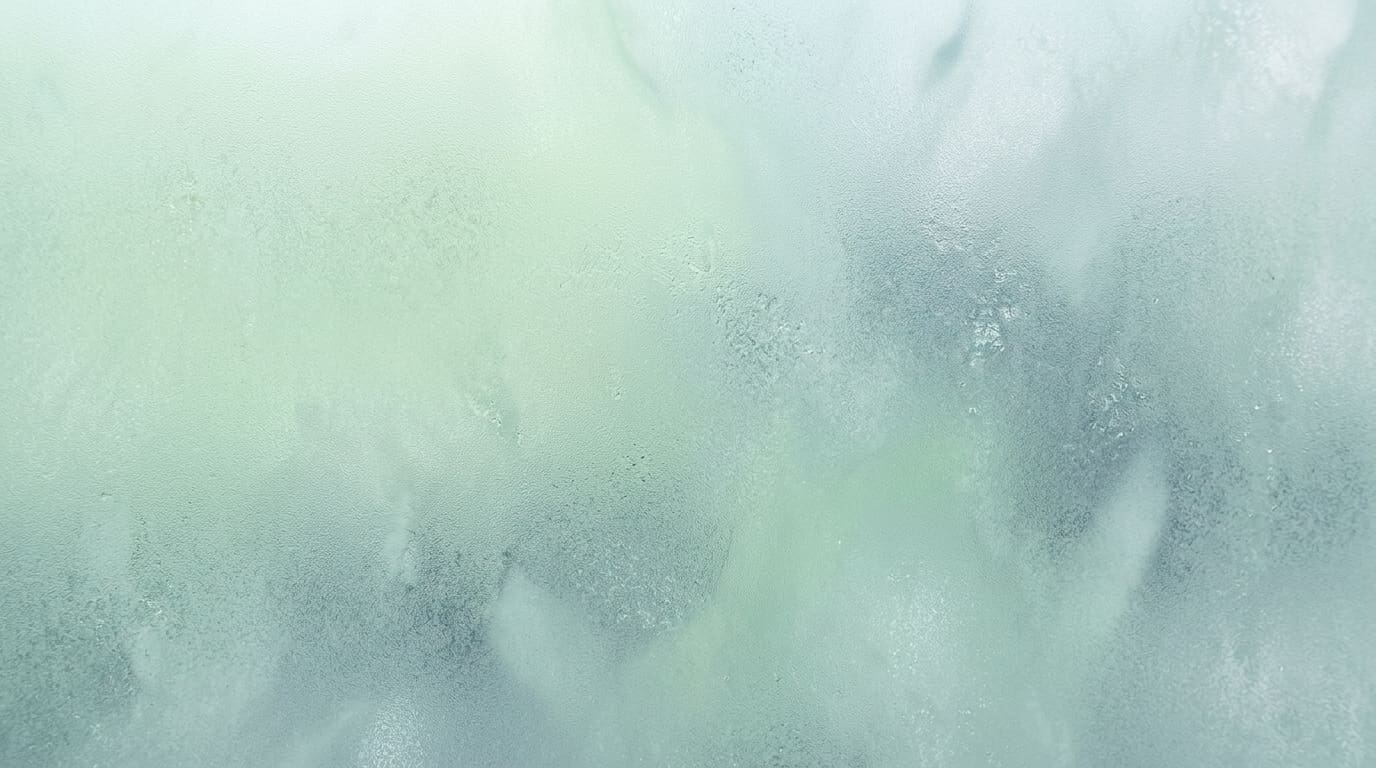 Abstract macro texture of soft dawn light diffused through frosted glass in pale green and cool blue-grey tones, no obje